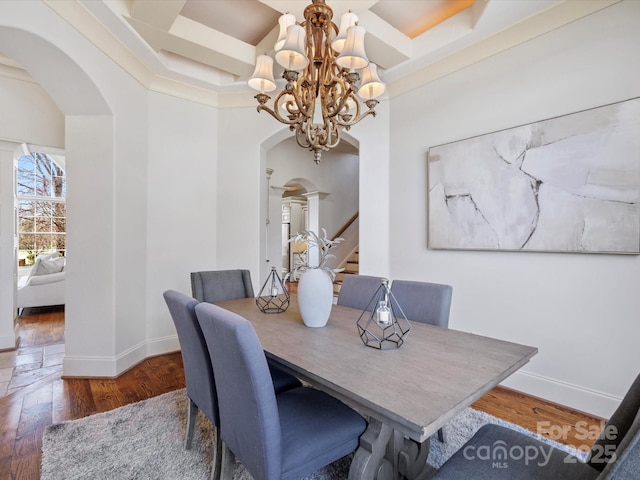 dining space with arched walkways, stairway, baseboards, and wood finished floors