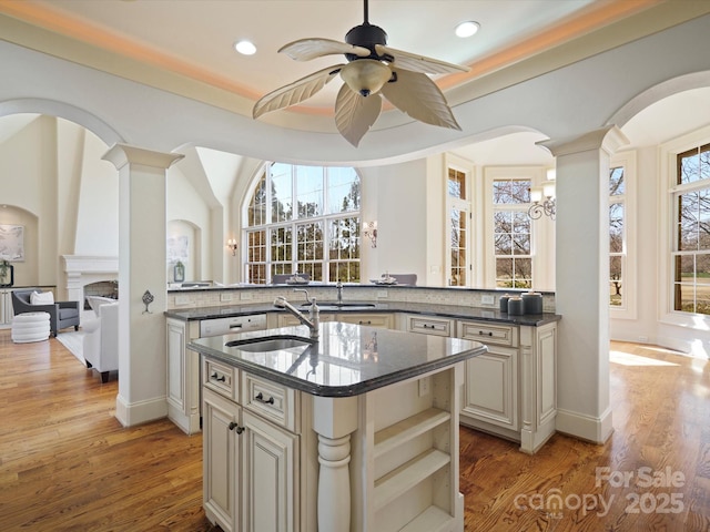 kitchen with light wood-style floors, a kitchen island with sink, cream cabinetry, and a sink