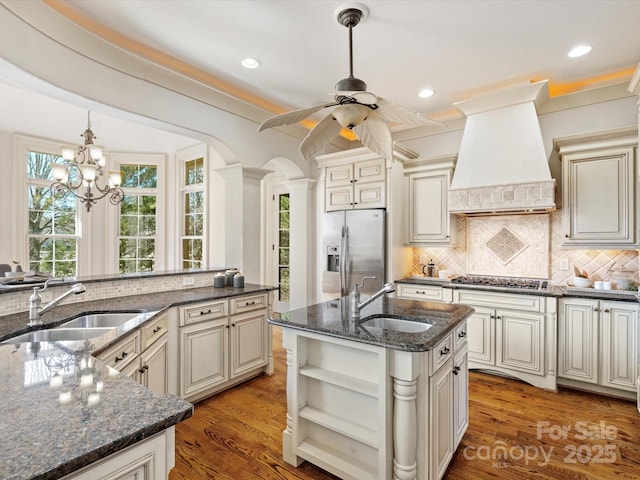 kitchen featuring stainless steel appliances, cream cabinetry, premium range hood, and a sink