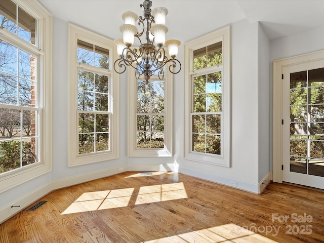 dining space featuring a healthy amount of sunlight, a notable chandelier, baseboards, and wood finished floors