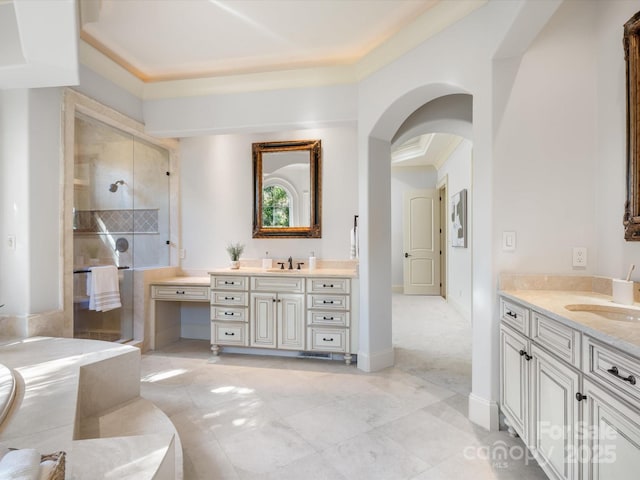 full bath featuring baseboards, two vanities, a tile shower, and a sink