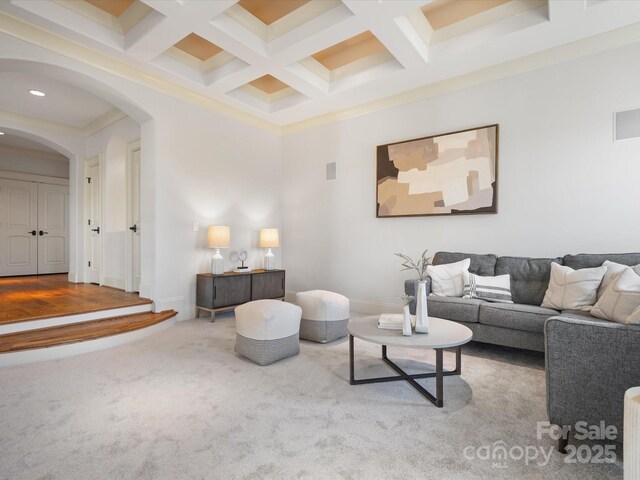 carpeted living room with baseboards, arched walkways, coffered ceiling, and beam ceiling