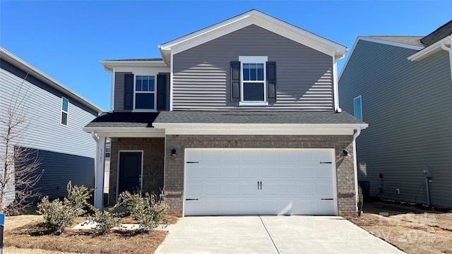 traditional home featuring a garage, concrete driveway, brick siding, and roof with shingles