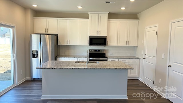 kitchen featuring stainless steel appliances, a kitchen island with sink, white cabinetry, and light stone counters