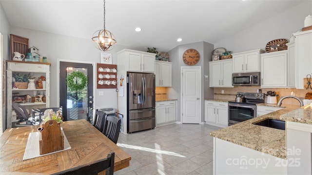 kitchen featuring hanging light fixtures, light stone countertops, sink, appliances with stainless steel finishes, and white cabinets