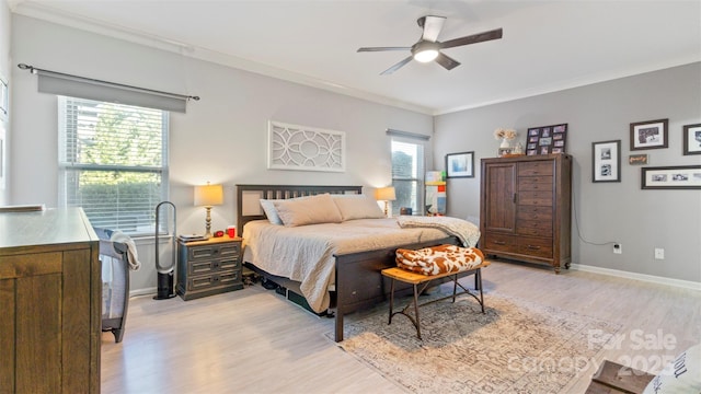 bedroom with multiple windows, ornamental molding, ceiling fan, and light hardwood / wood-style floors