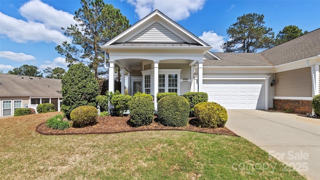view of front of property with a front yard, a standing seam roof, driveway, and a garage