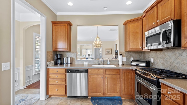 kitchen featuring a sink, light countertops, brown cabinets, crown molding, and stainless steel appliances