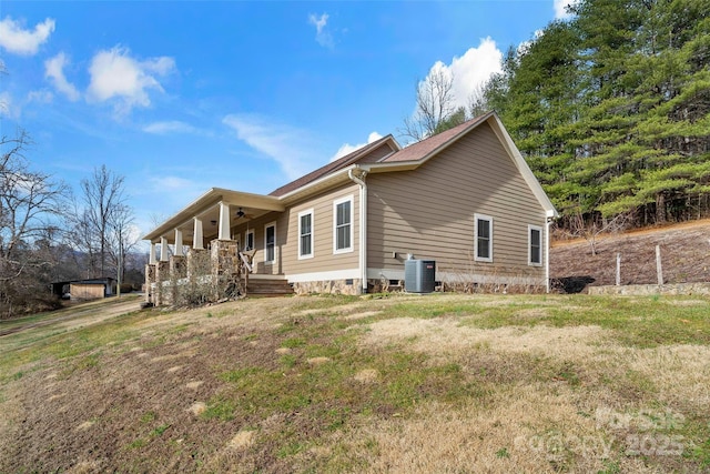 view of property exterior featuring central AC unit, covered porch, and a lawn