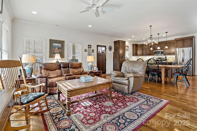 living room with crown molding, ceiling fan with notable chandelier, and dark hardwood / wood-style floors