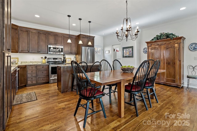 dining area with ornamental molding, a chandelier, and hardwood / wood-style floors