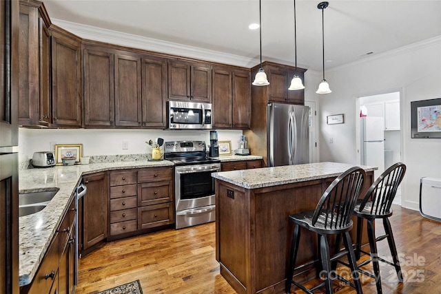 kitchen with light stone counters, dark brown cabinetry, stainless steel appliances, and a center island