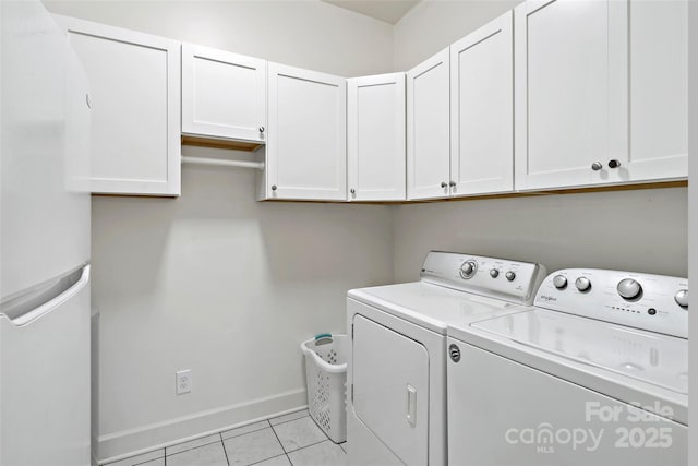 washroom with light tile patterned flooring, cabinets, and washing machine and dryer