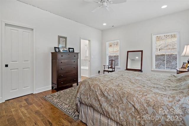 bedroom featuring ceiling fan, connected bathroom, dark hardwood / wood-style flooring, and multiple windows