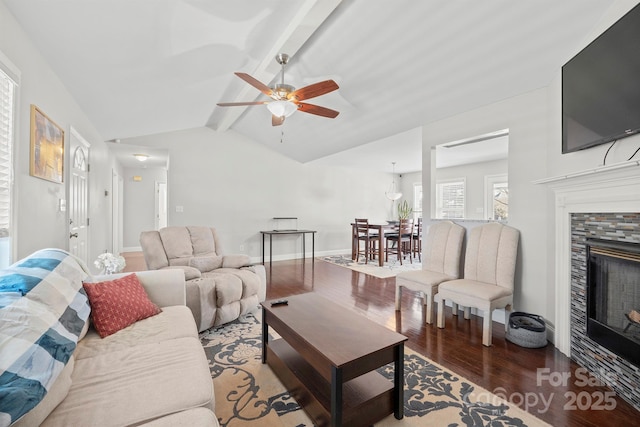 living room featuring ceiling fan, hardwood / wood-style floors, a tile fireplace, and vaulted ceiling with beams