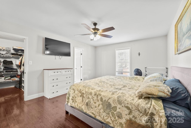 bedroom featuring a spacious closet, dark wood-type flooring, a closet, and ceiling fan