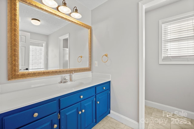 bathroom with vanity, tile patterned flooring, plenty of natural light, and a textured ceiling