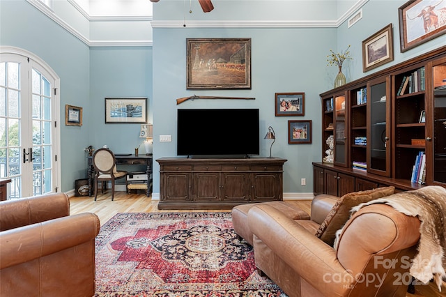 living room with a towering ceiling, french doors, ceiling fan, and light wood-type flooring