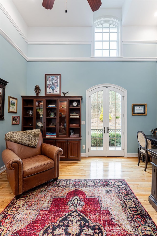 living room featuring light wood-type flooring, a towering ceiling, ceiling fan, and french doors