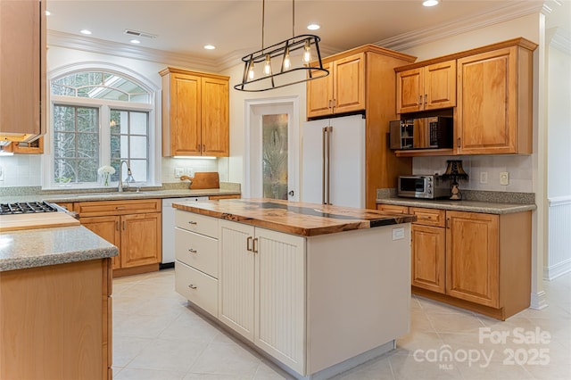 kitchen featuring butcher block countertops, decorative light fixtures, ornamental molding, a center island, and white appliances