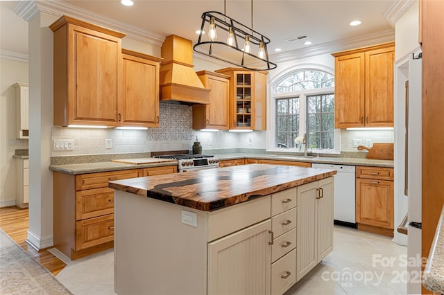 kitchen featuring premium range hood, wood counters, dishwasher, sink, and a center island