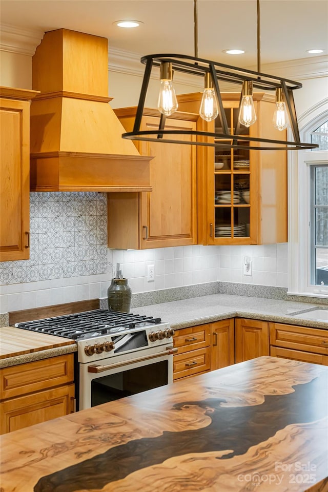 kitchen featuring sink, crown molding, decorative light fixtures, stainless steel range, and custom range hood