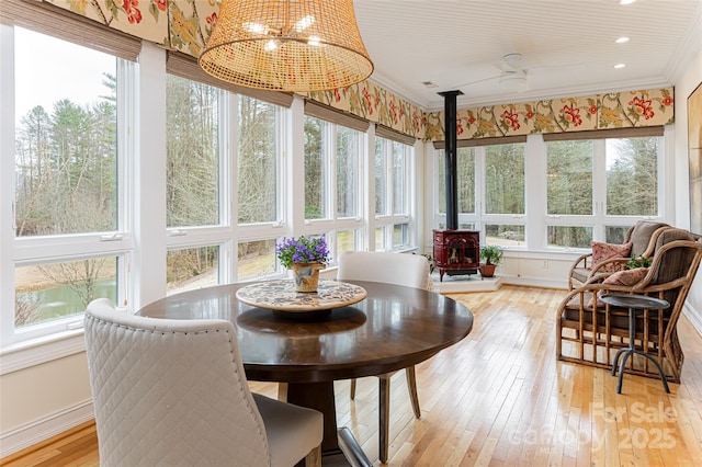 sunroom featuring ceiling fan and a wood stove