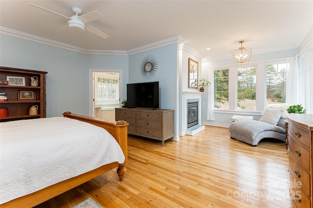 bedroom featuring crown molding, ensuite bath, ceiling fan with notable chandelier, and light wood-type flooring