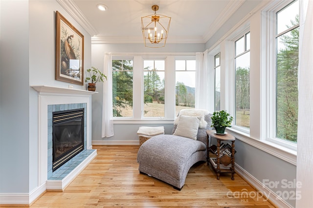 sunroom featuring a tiled fireplace, plenty of natural light, and a chandelier