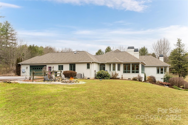 back of property with a garage, cooling unit, and a lawn