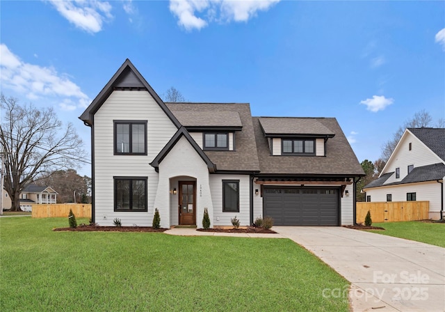 view of front of property with fence, a front lawn, concrete driveway, and roof with shingles