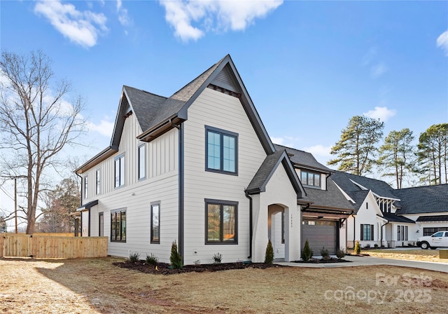 modern farmhouse style home with fence, board and batten siding, and a front yard