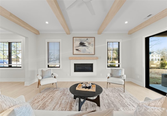 living room featuring a glass covered fireplace, beamed ceiling, and light wood finished floors