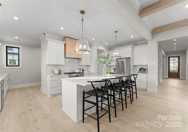 kitchen with pendant lighting, a center island with sink, light countertops, white cabinets, and high quality fridge