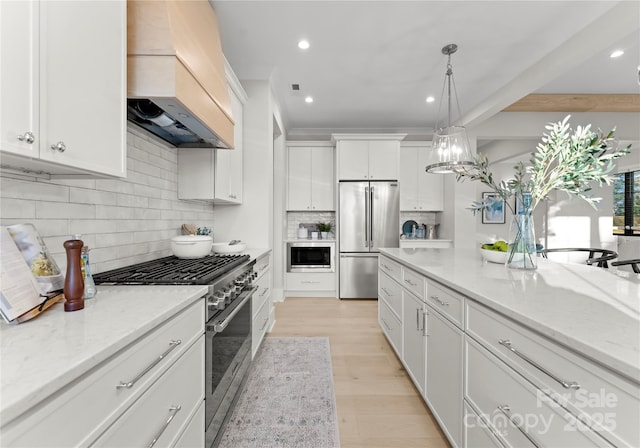 kitchen with premium range hood, appliances with stainless steel finishes, white cabinets, and light stone counters