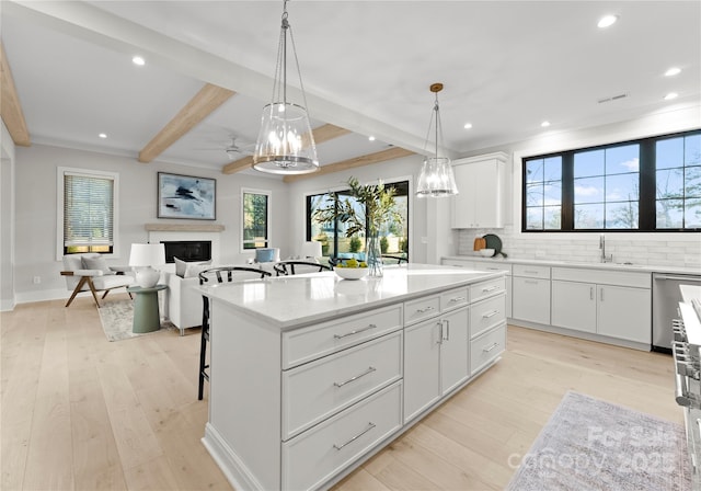 kitchen featuring white cabinets, a kitchen island, hanging light fixtures, and a fireplace