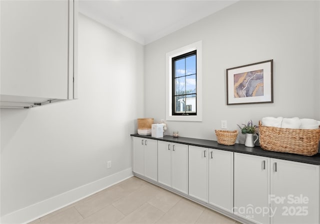 interior space featuring light tile patterned floors, ornamental molding, and baseboards