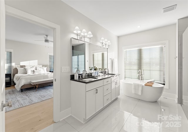 bathroom featuring a sink, a freestanding tub, ensuite bath, and visible vents