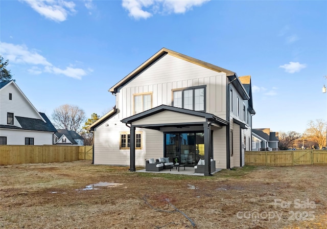 rear view of property with board and batten siding, a fenced backyard, and an outdoor living space