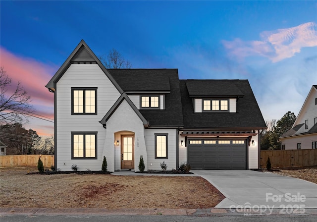 view of front of home with a shingled roof, fence, and driveway