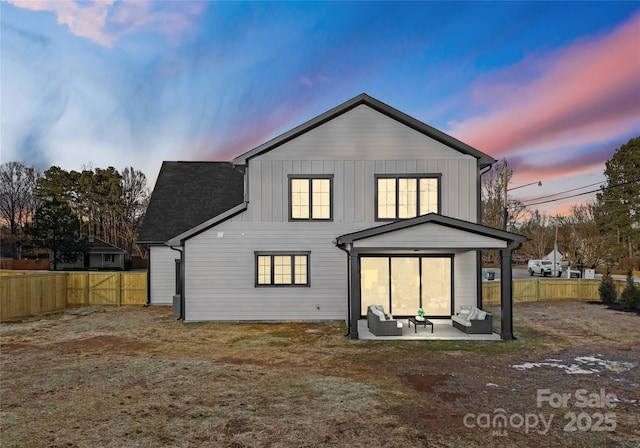 back of property at dusk featuring board and batten siding, a patio area, and a fenced backyard