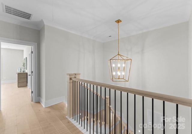 hallway with an upstairs landing, visible vents, baseboards, light wood-type flooring, and an inviting chandelier