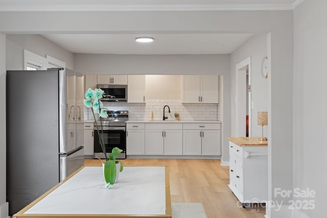 kitchen featuring sink, white cabinetry, tasteful backsplash, light wood-type flooring, and stainless steel appliances