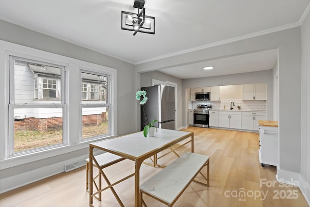 dining room featuring ornamental molding, light hardwood / wood-style floors, and sink