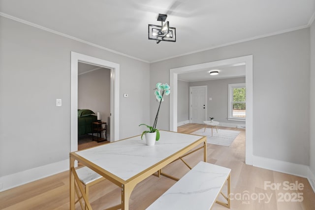 dining space with crown molding and light hardwood / wood-style flooring