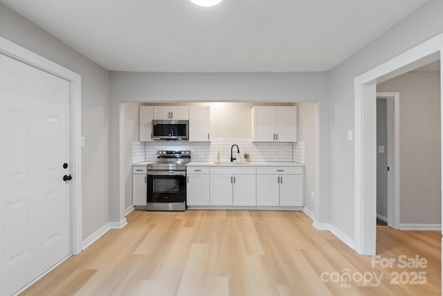 kitchen featuring appliances with stainless steel finishes, sink, white cabinets, and backsplash