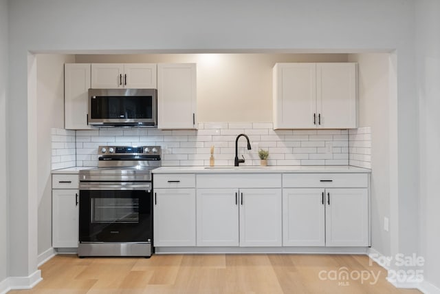 kitchen featuring sink, light wood-type flooring, white cabinets, and appliances with stainless steel finishes