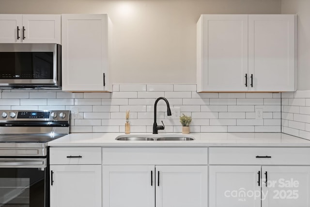 kitchen with appliances with stainless steel finishes, sink, white cabinets, and backsplash