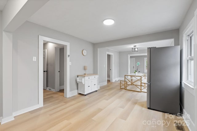 kitchen featuring light hardwood / wood-style floors, stainless steel refrigerator, and white cabinets