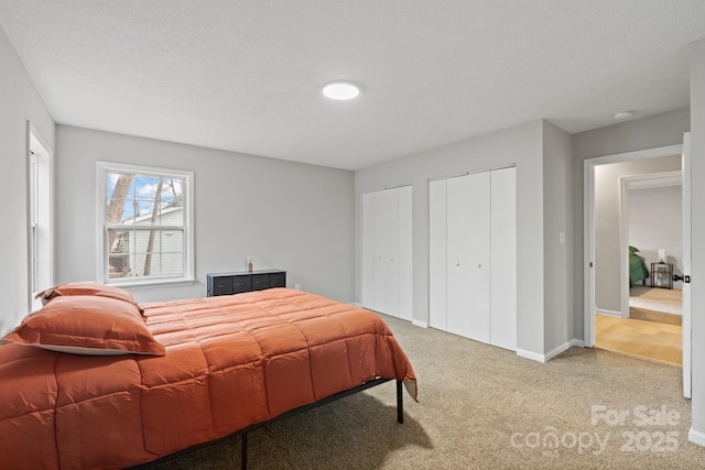 carpeted bedroom with two closets and a textured ceiling